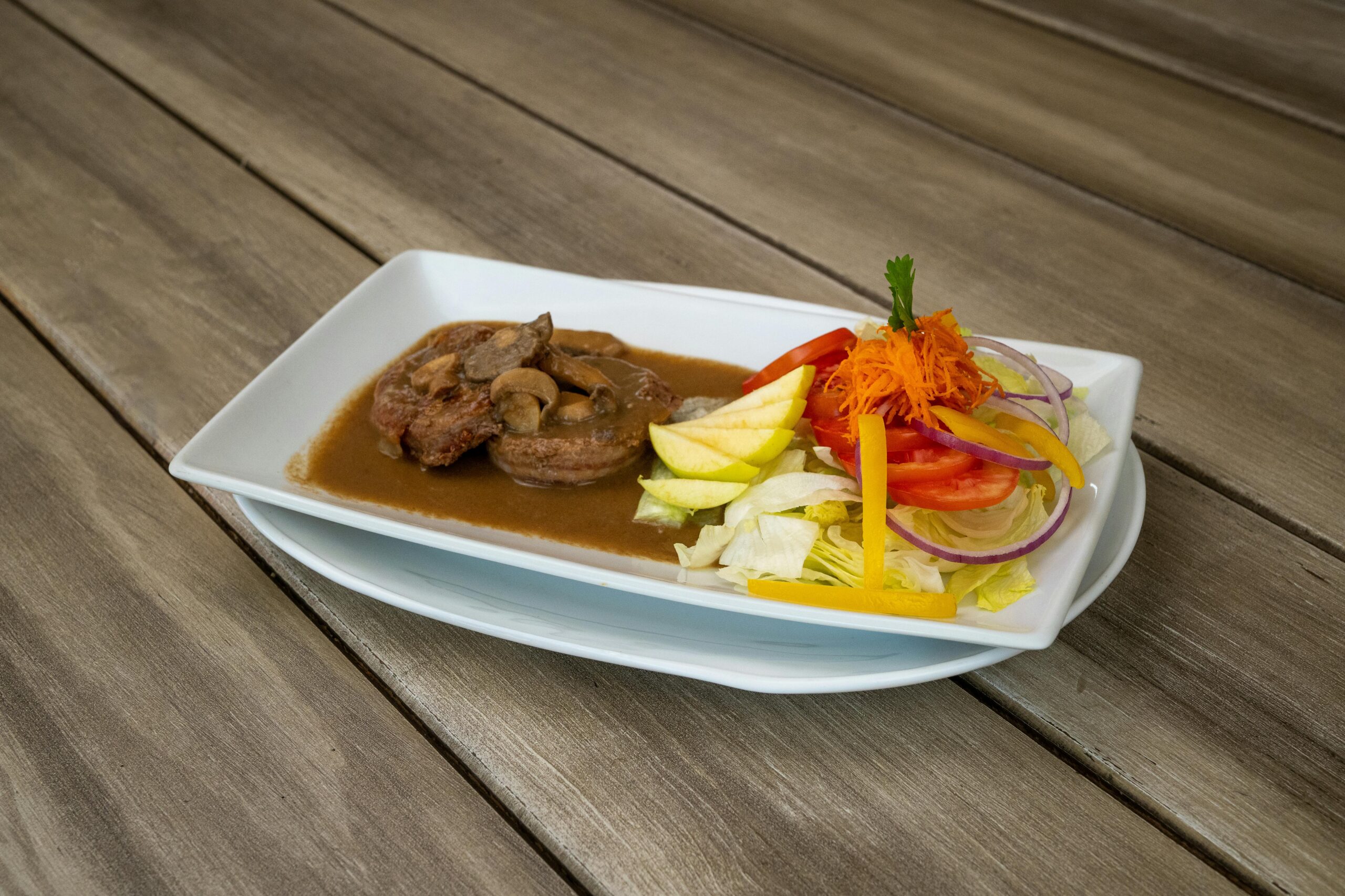 Brutzelndes Steak mit Pilzsauce und frischem Salat auf einem rustikalen Holztisch. Ein perfekter Gaumenschmaus.