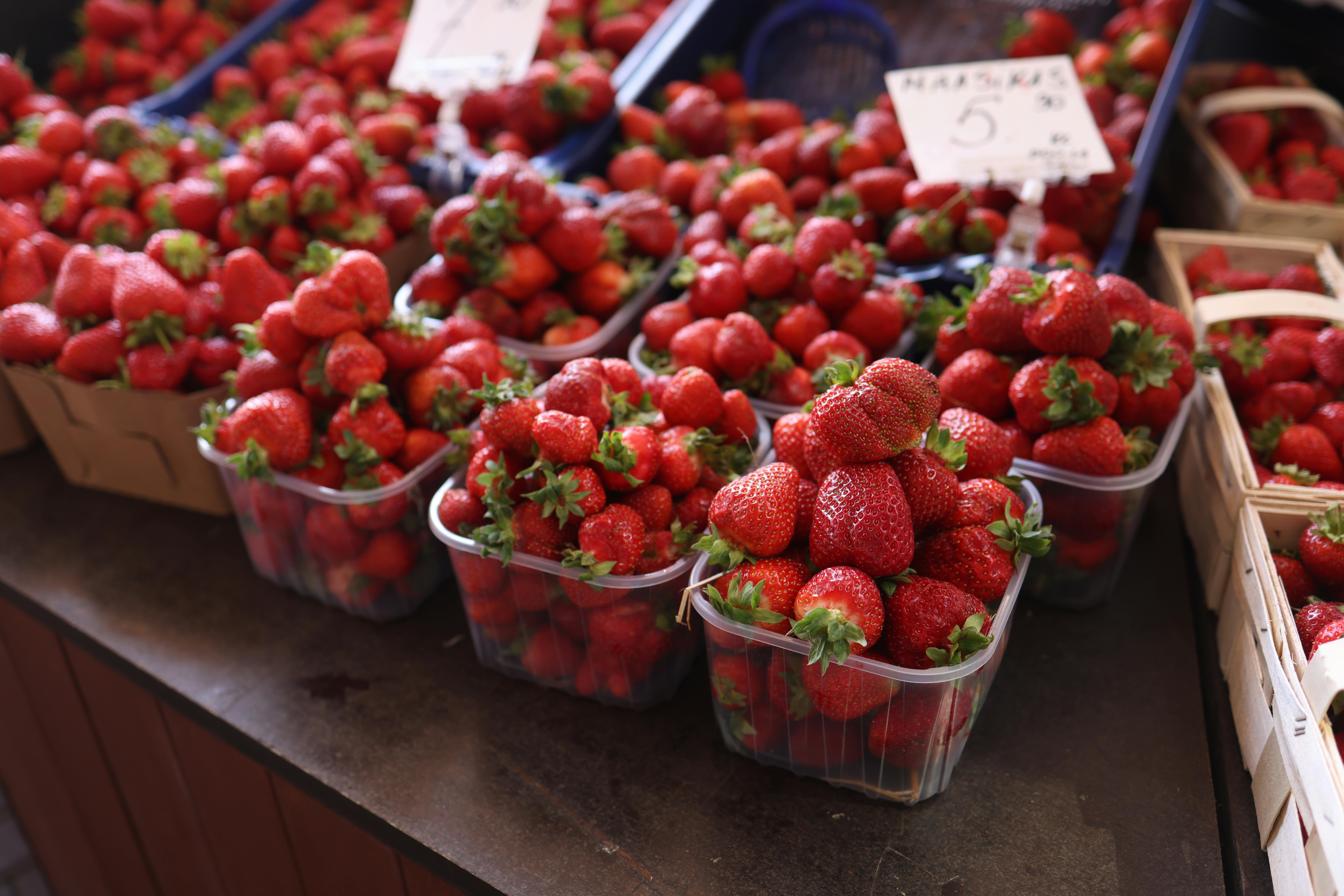 Leuchtend rote Erdbeeren in Körben auf einem Markt im Freien, die Frische und Fülle demonstrieren.