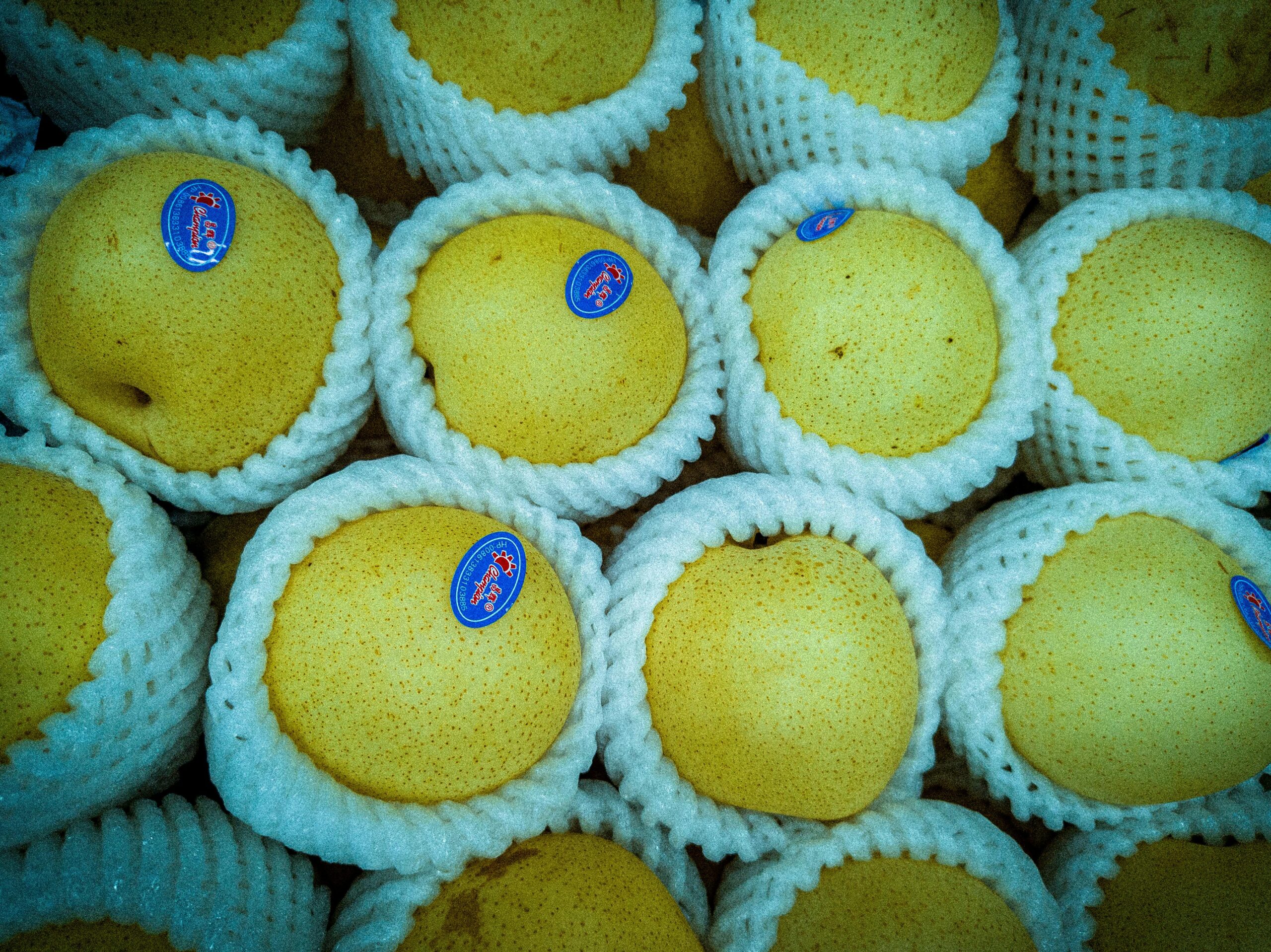 Eine Auswahl an frischen Birnen, verpackt in Schaumstoffnetzen, auf einem Markt in Jessore, Bangladesch.